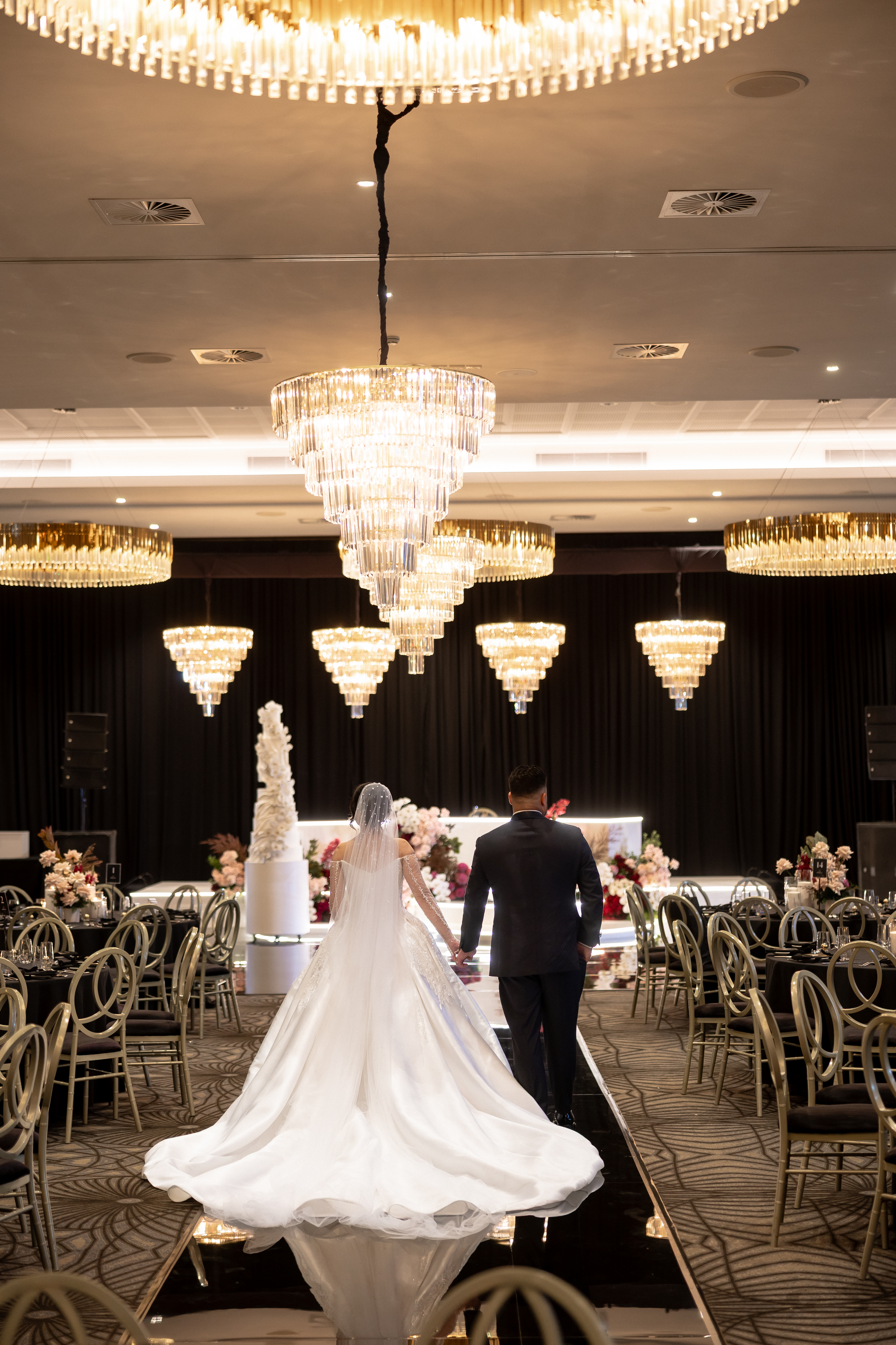 Wedding reception atmosphere with couple walking down the aisle between chandeliers